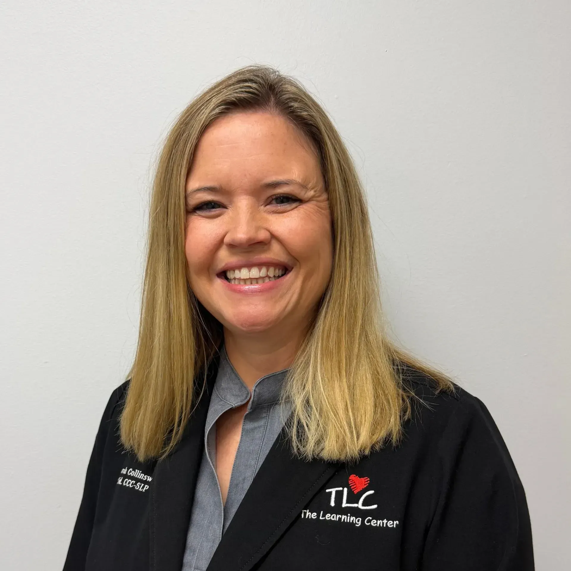 Woman in black jacket with TLC logo smiling at the camera.