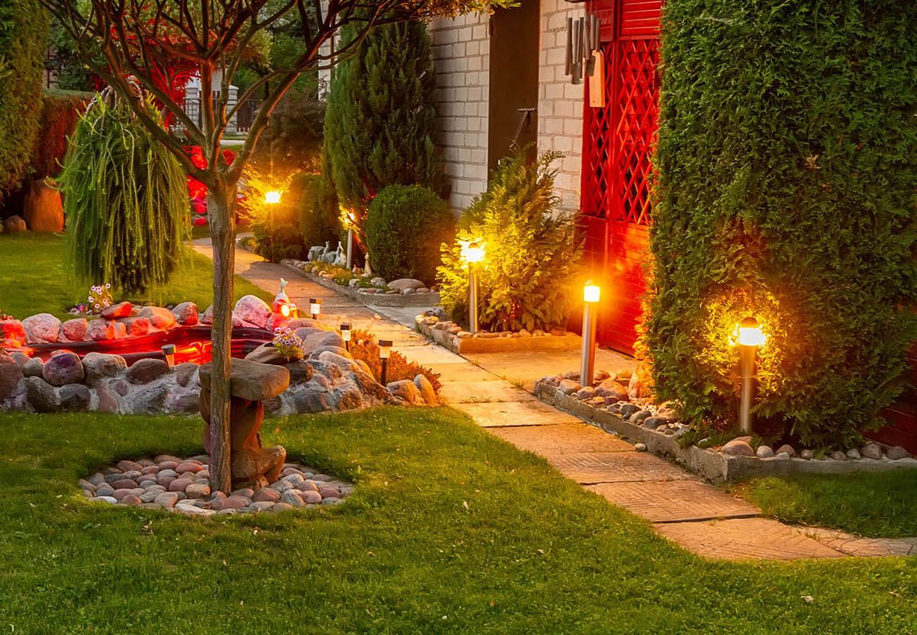 A path leading to a house with a lot of lights on it.