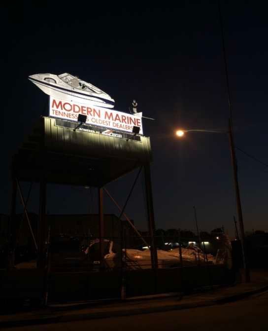 A modern marine sign is lit up at night.