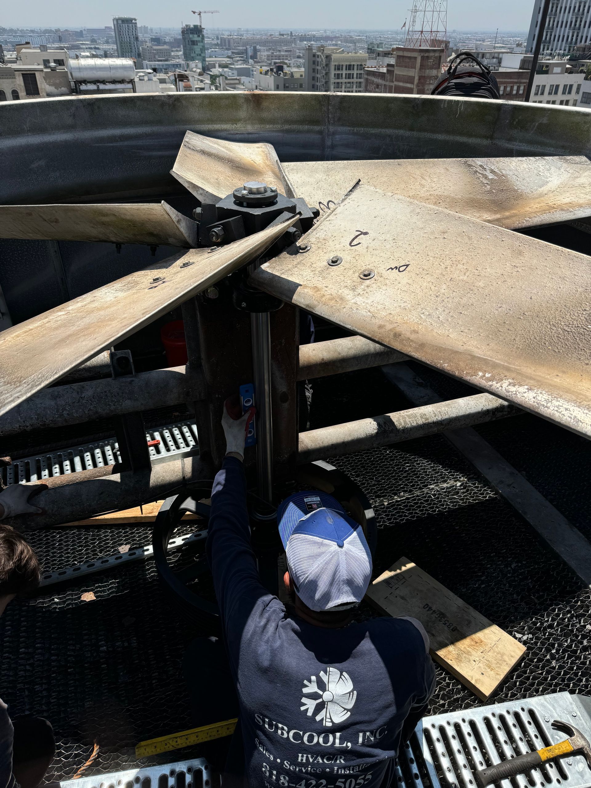 A man is working on a fan on top of a building