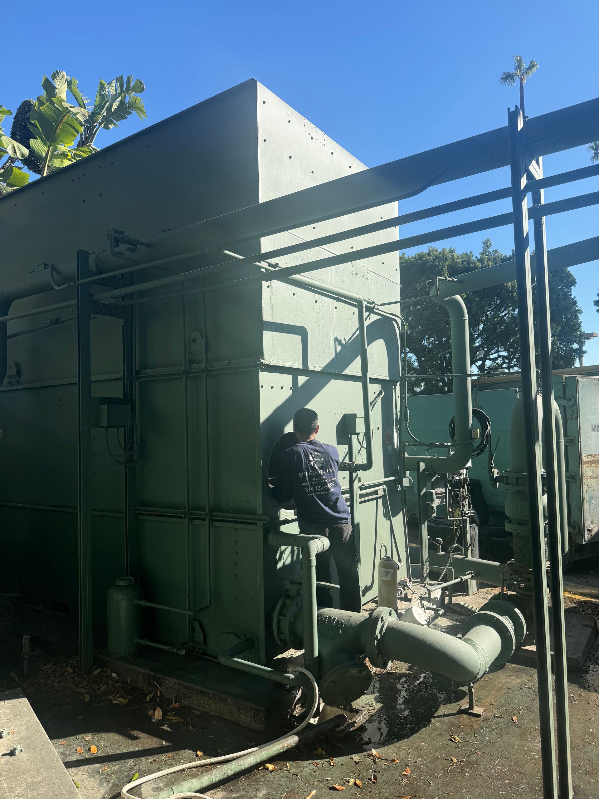 A man is working on a machine in front of a building.