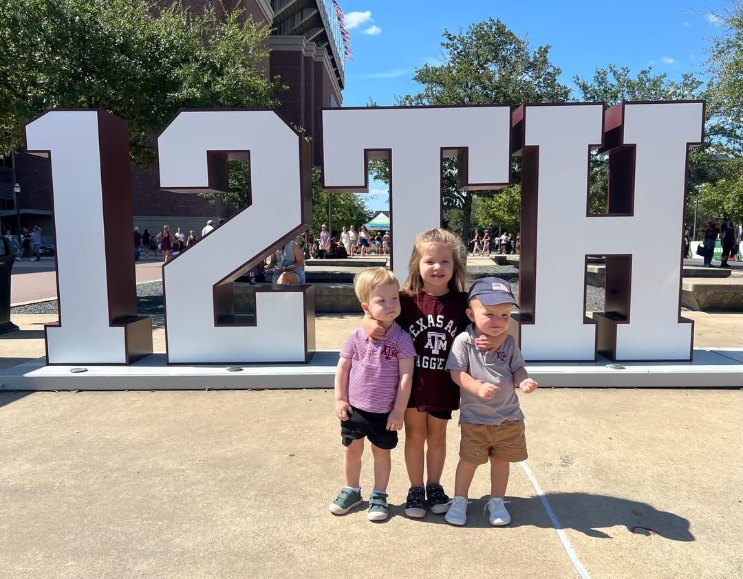 Three young children pose in front of a 