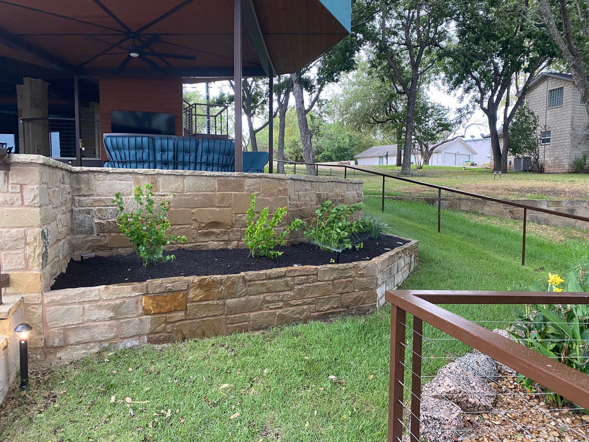 A backyard with a brick wall and a fence surrounding it.