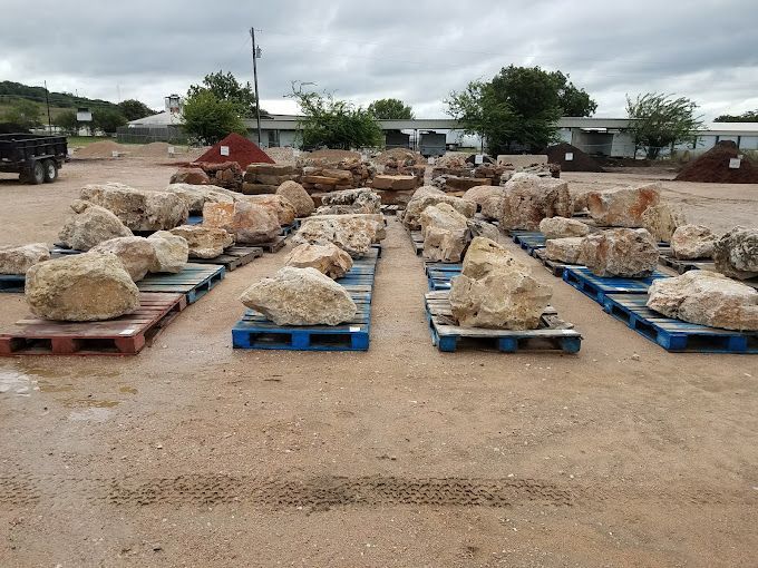 A bunch of rocks on pallets in a field