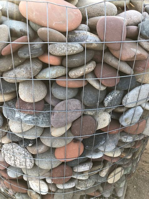 A pile of rocks sitting inside of a wire fence.