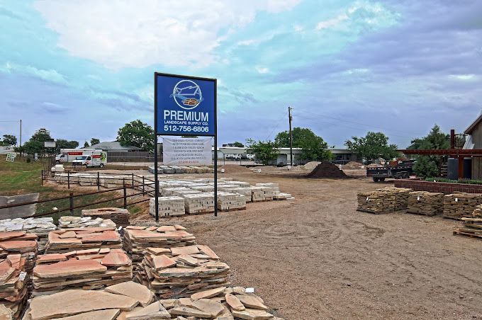 A large pile of rocks is sitting in a dirt field next to a sign.