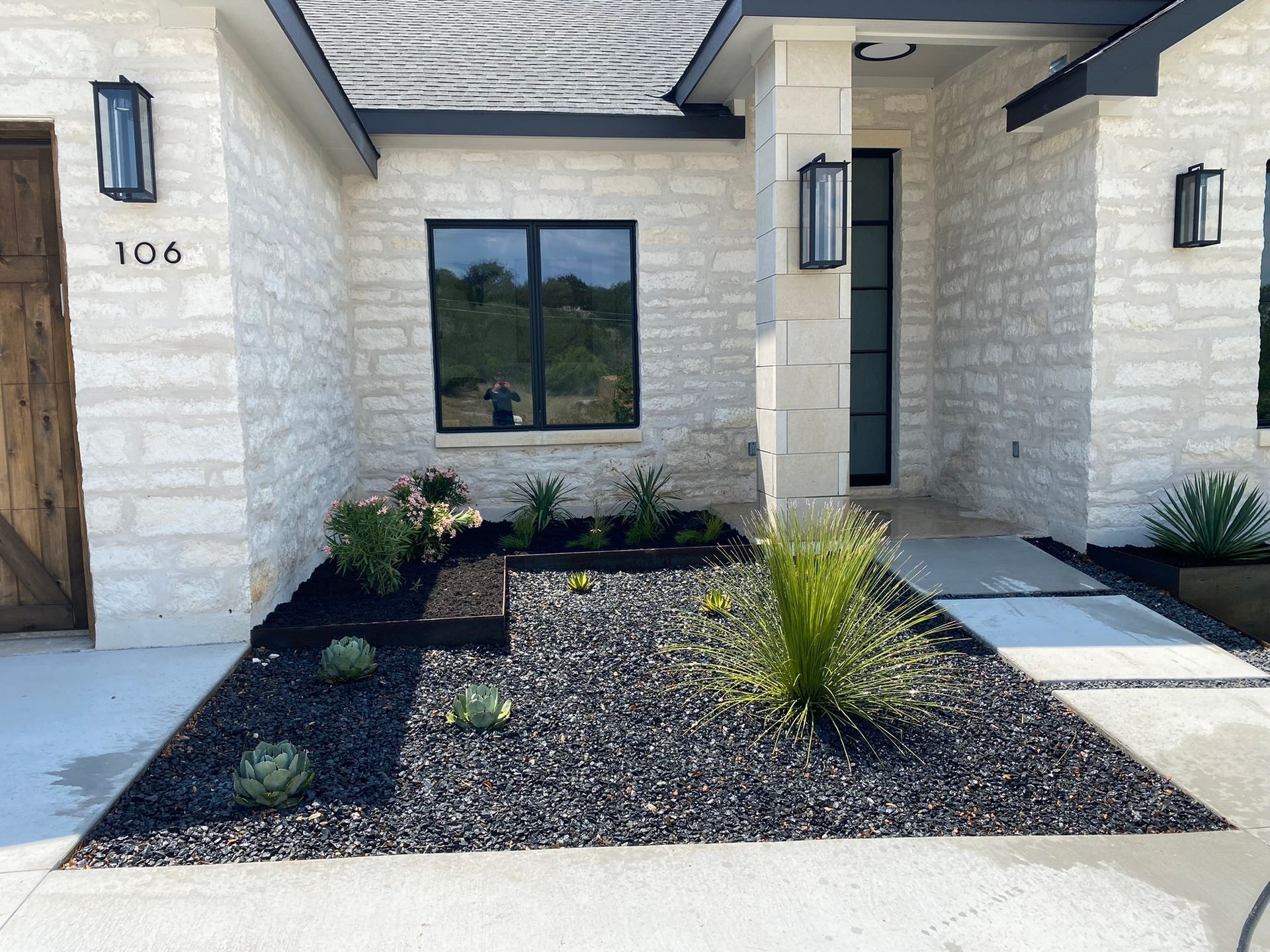 A white brick house with a garden in front of it