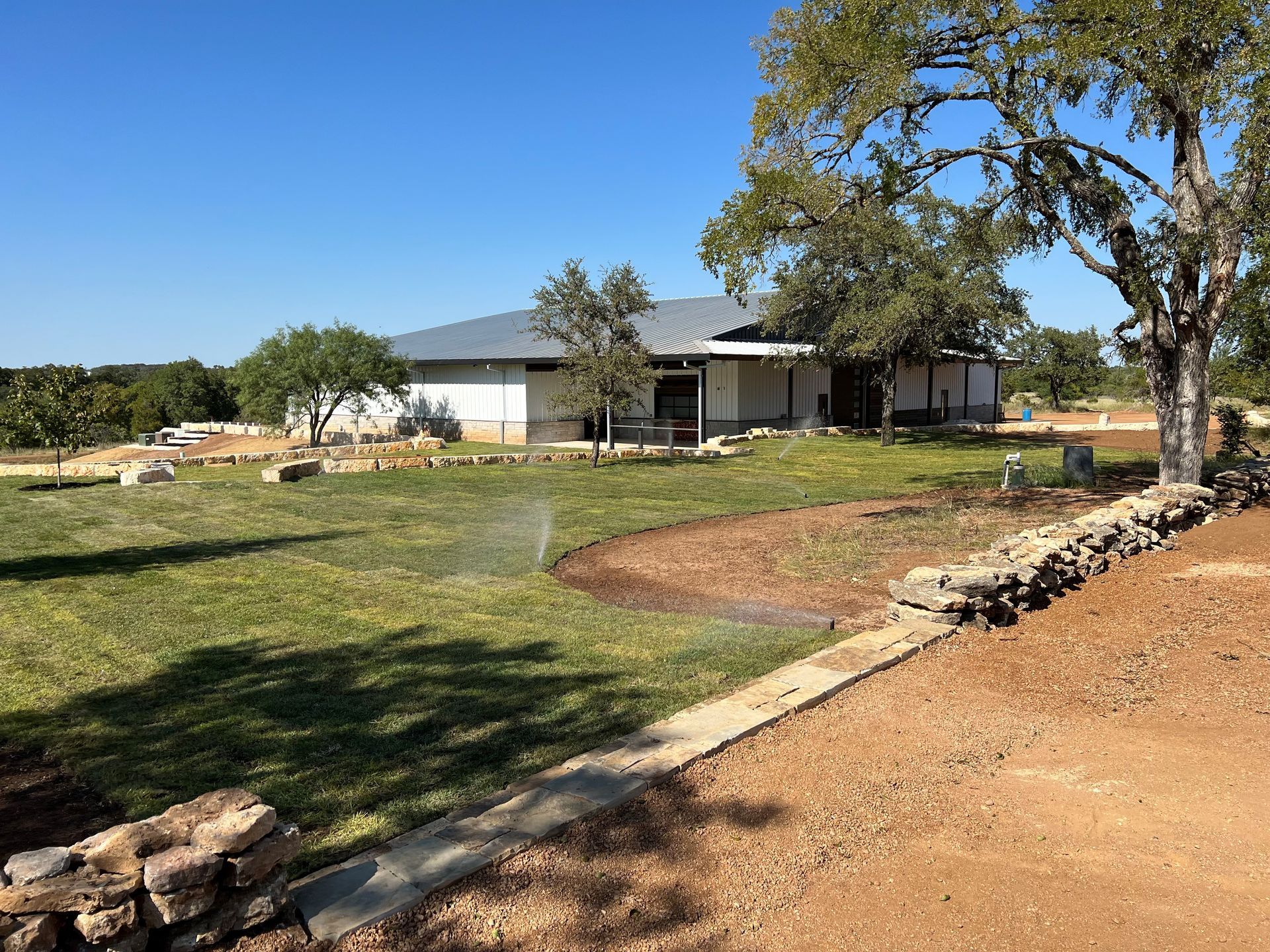 A large house is sitting in the middle of a lush green field.