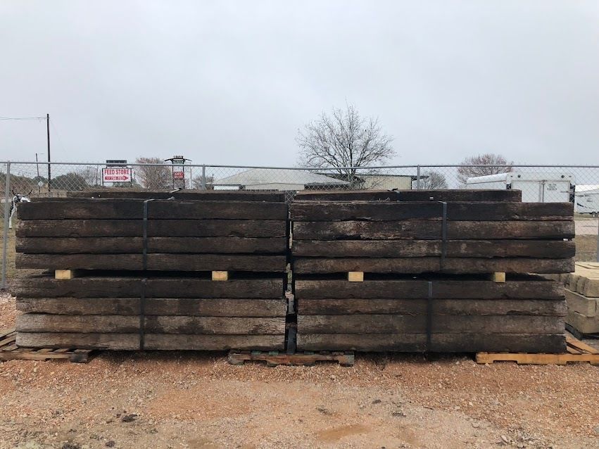 A pile of wooden beams stacked on top of each other in a dirt field.