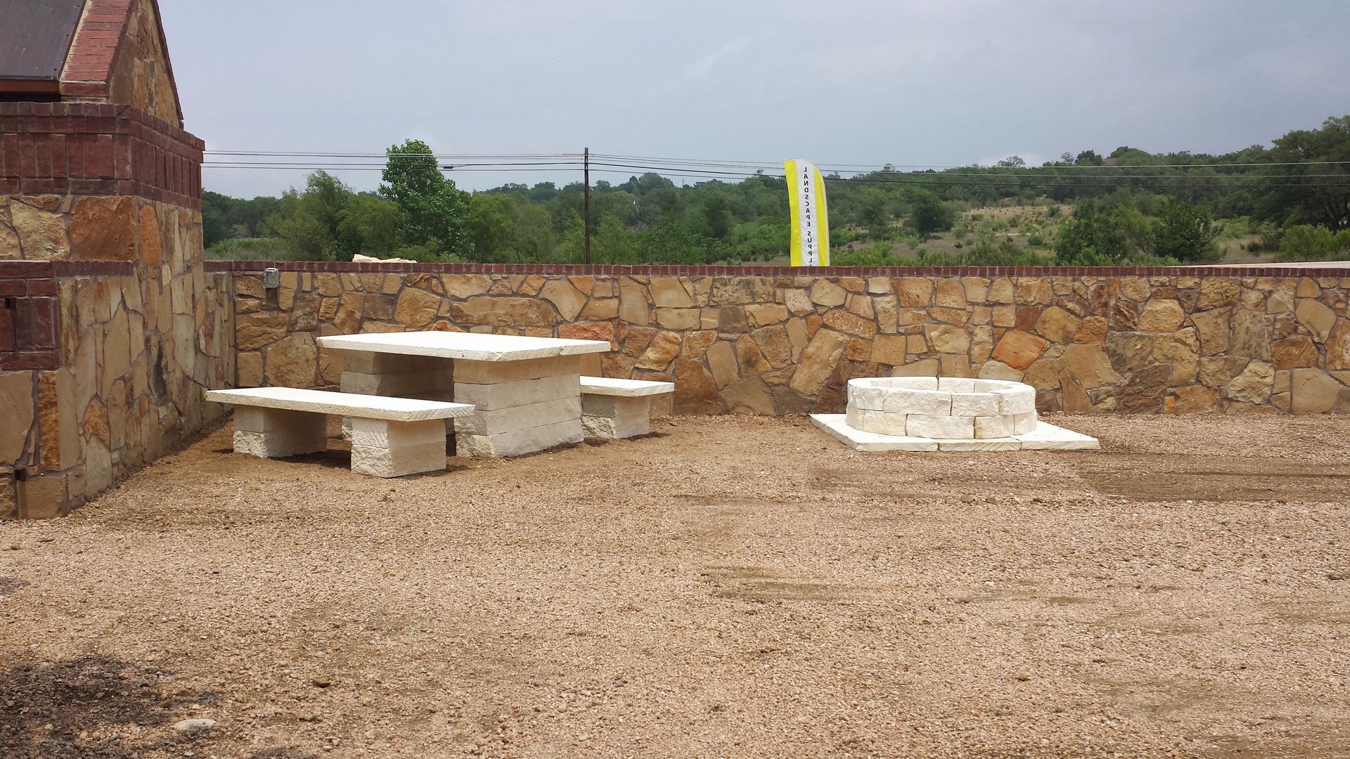 A stone wall with a picnic table and benches in front of it