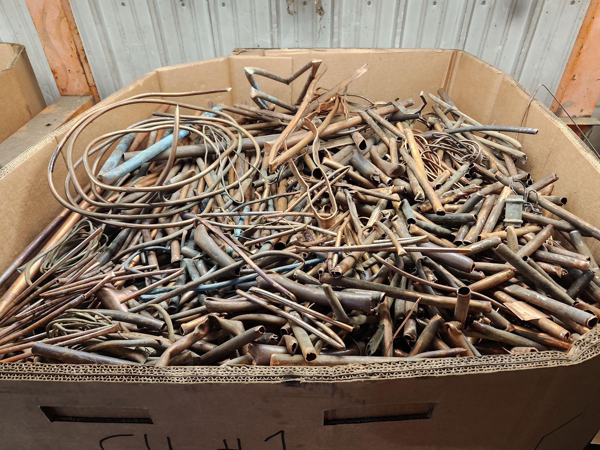 A cardboard box filled with a lot of metal scraps.