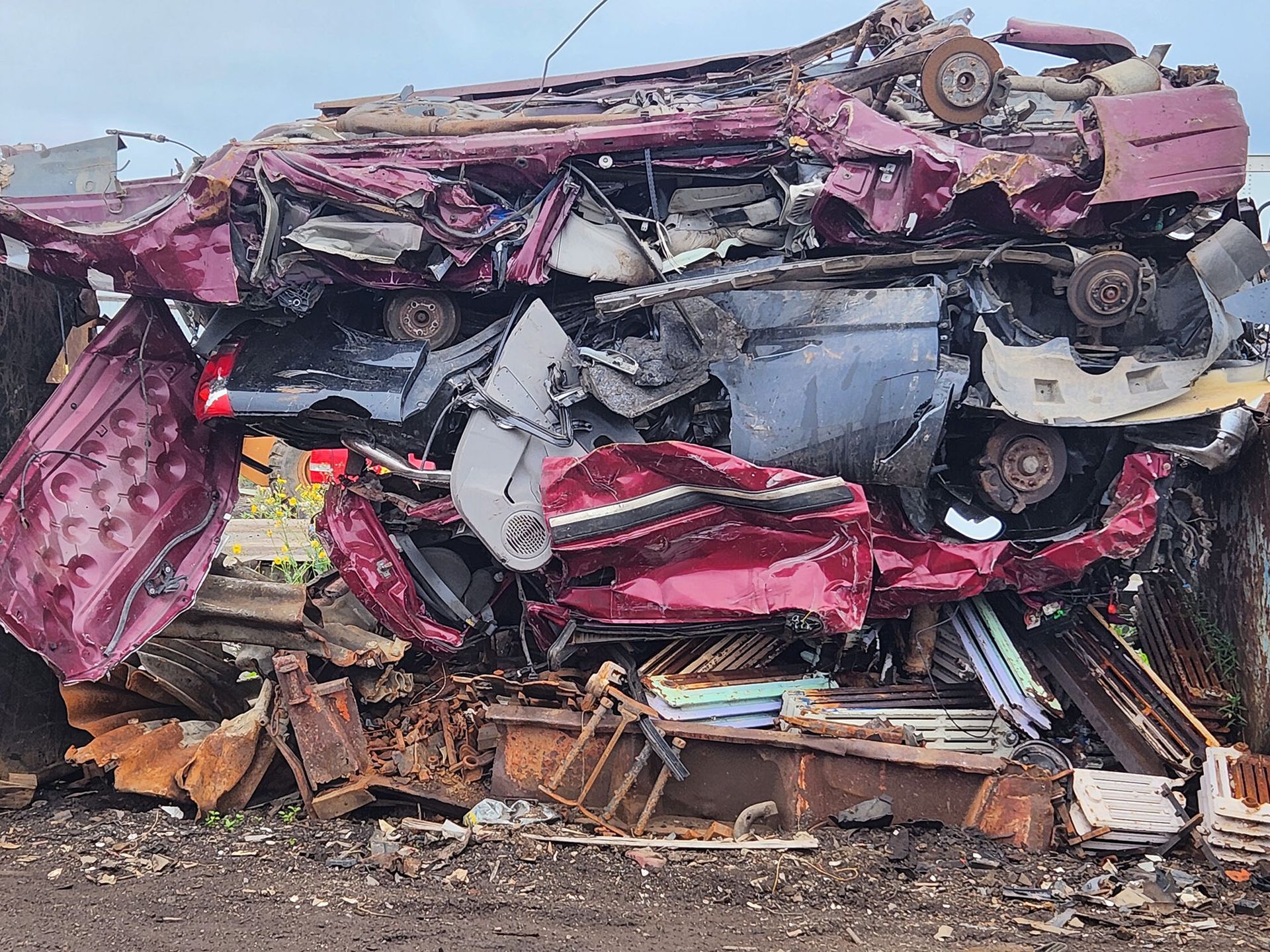 A purple car is sitting on top of a pile of scrap metal.