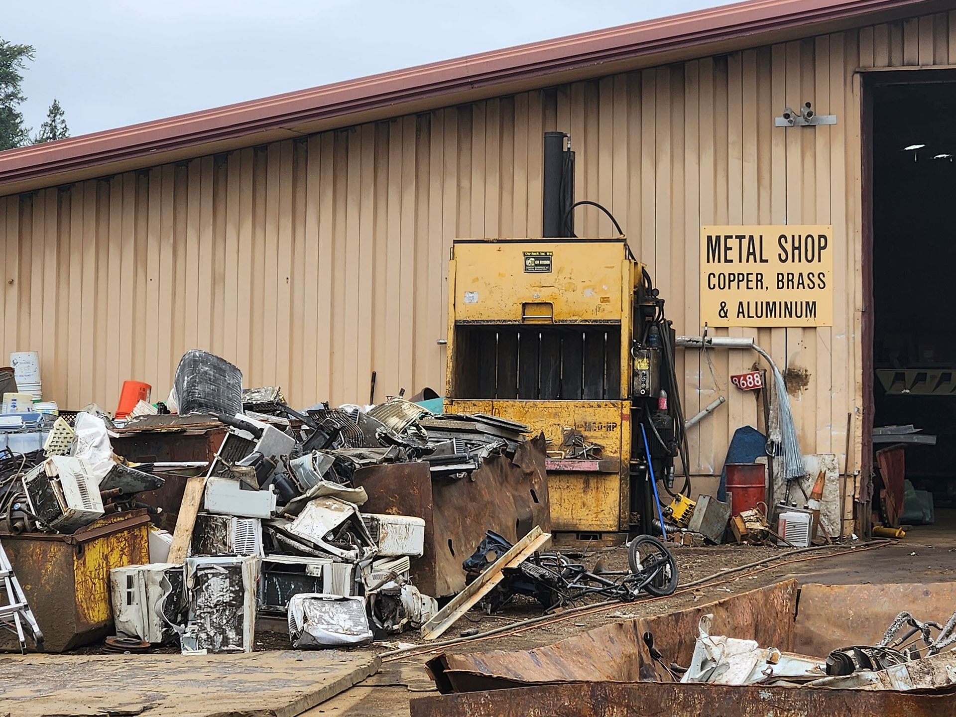 A metal shop with a large pile of scrap metal in front of it