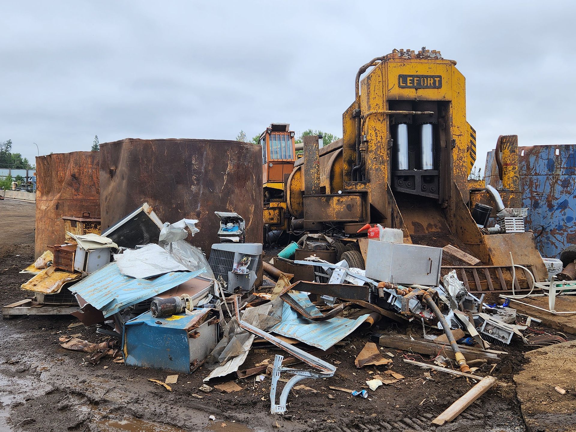 A pile of scrap metal with a yellow machine in the background.