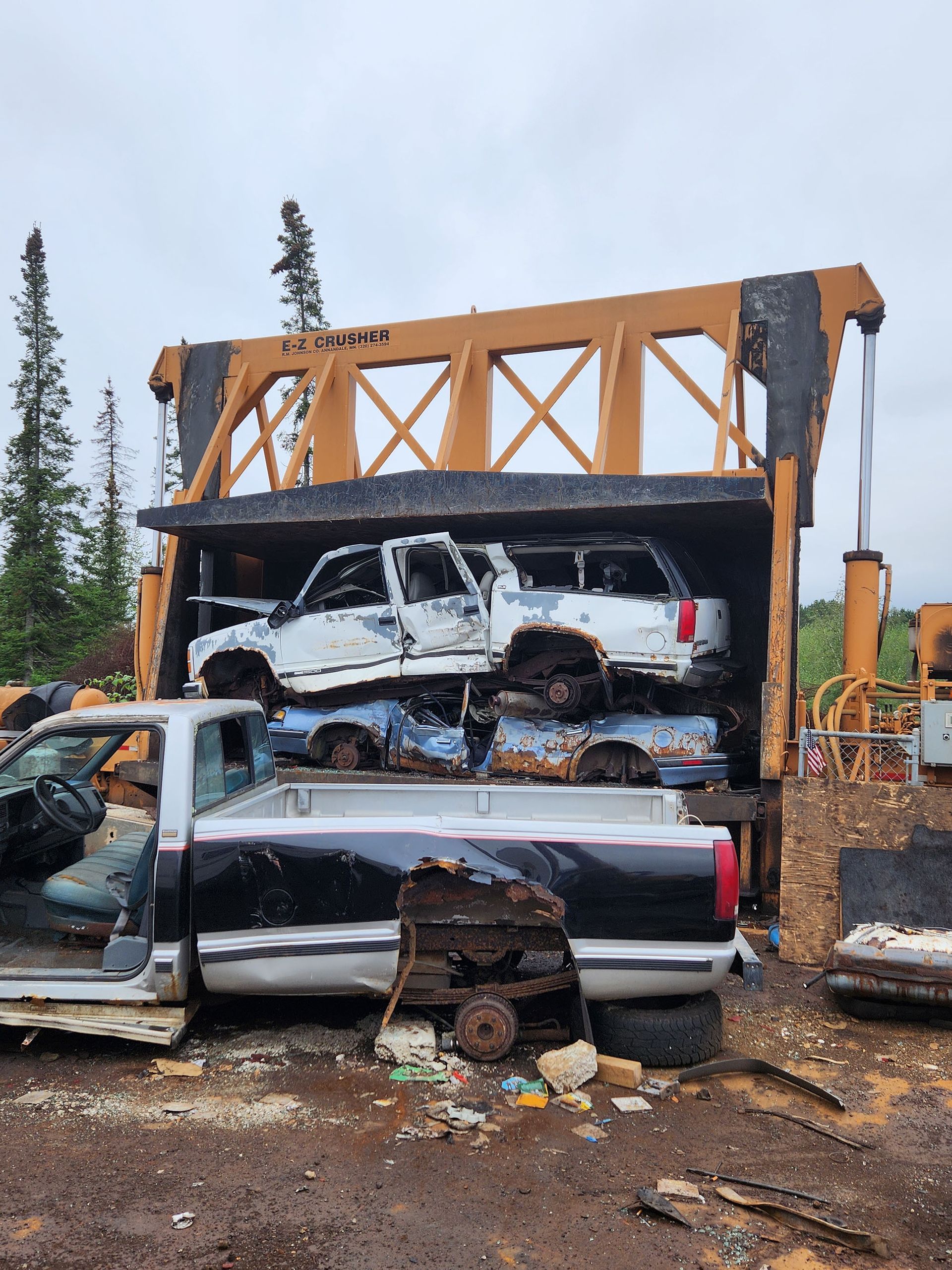 A truck is sitting in a pile of wrecked cars