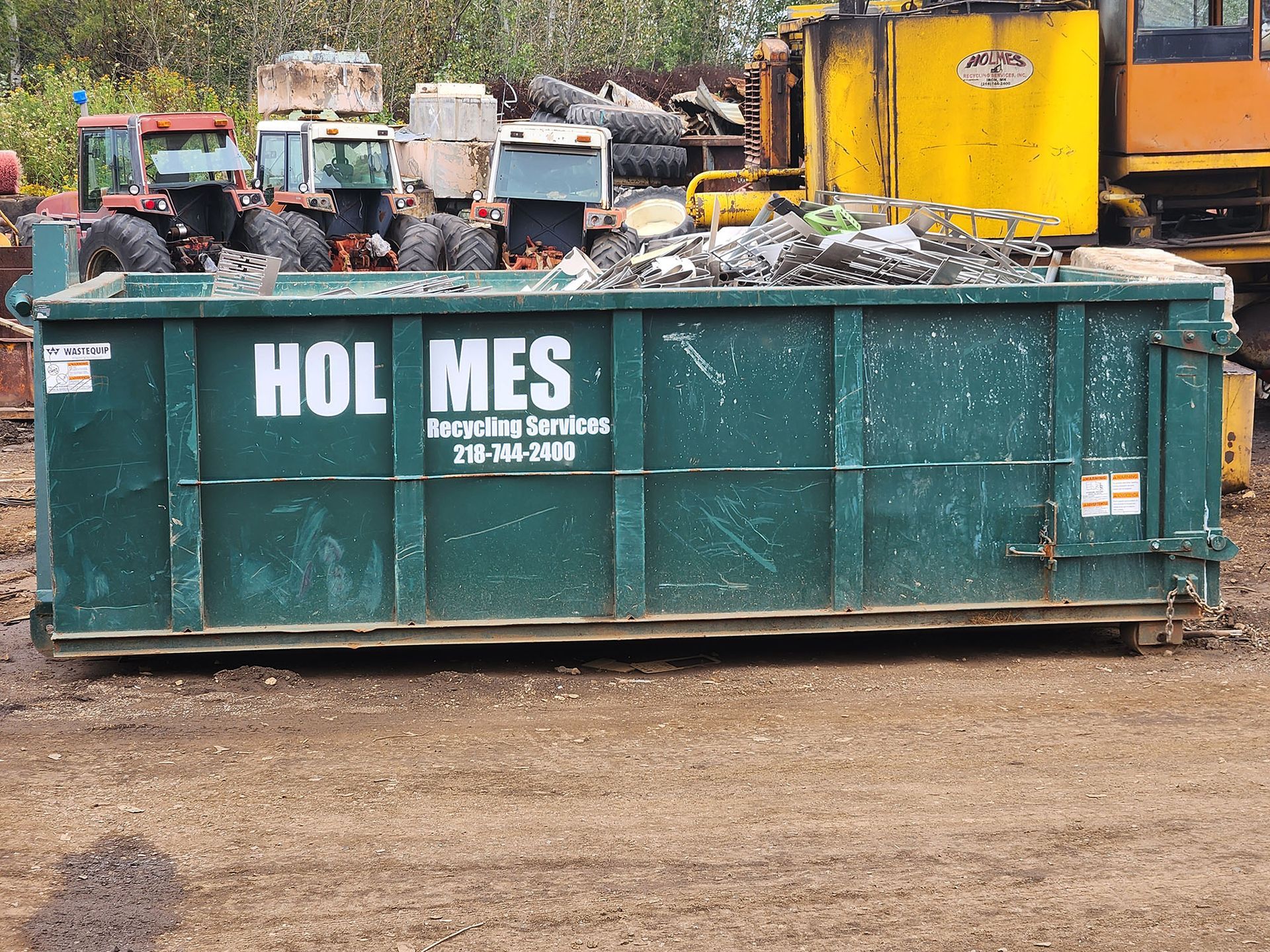 A green dumpster that says hol mes on it