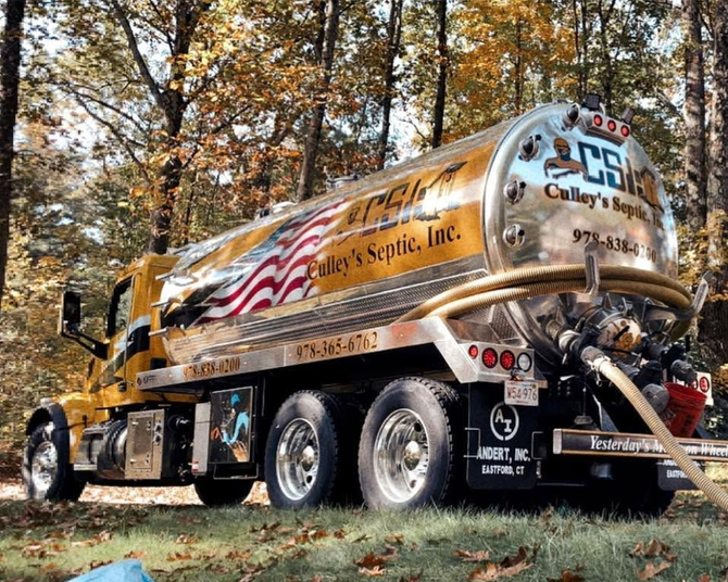 Gold septic tanker truck parked in autumn woods