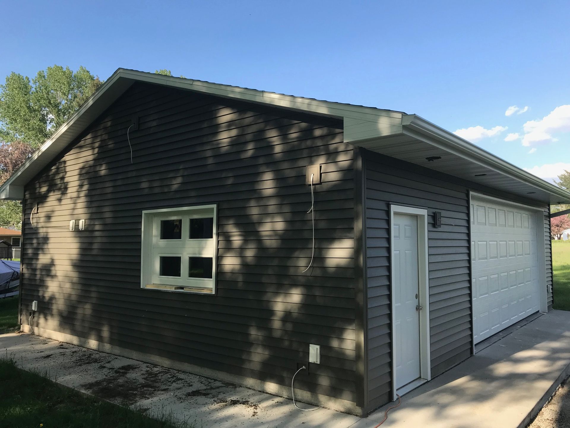 Dark brown house exterior with white garage door and side entrance in daylight