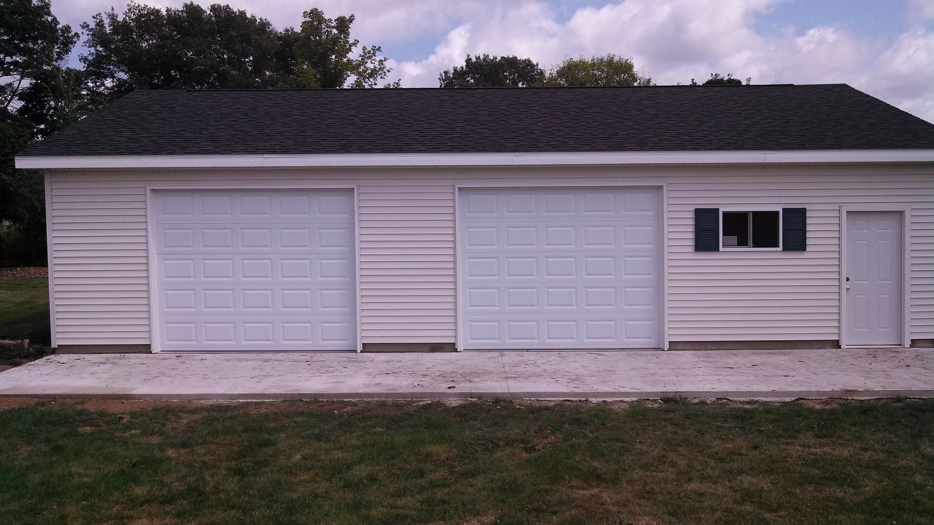 White two-car garage with a side door and window on a house at dusk