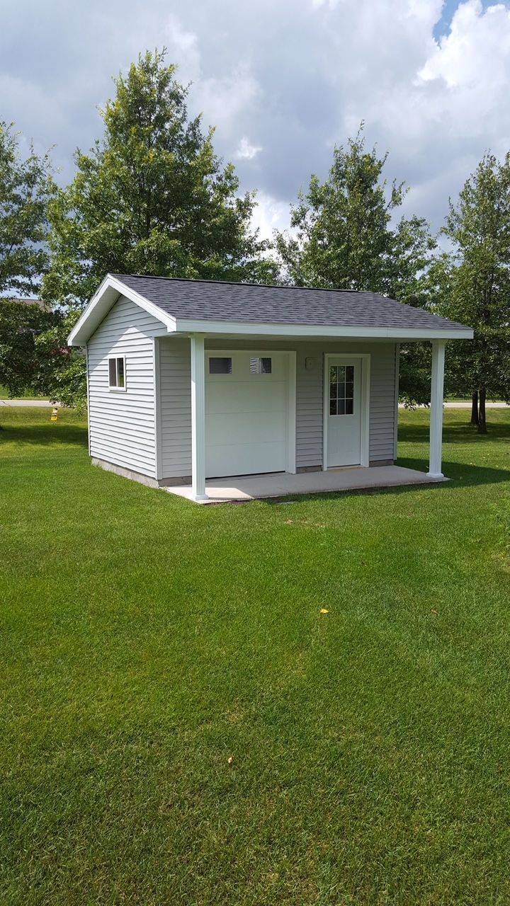 Small white cottage with a porch on a grassy lawn under a partly cloudy sky