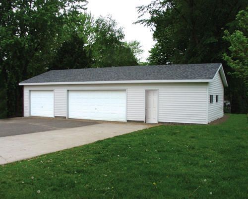 Three-door white detached garage beside a driveway and grassy yard