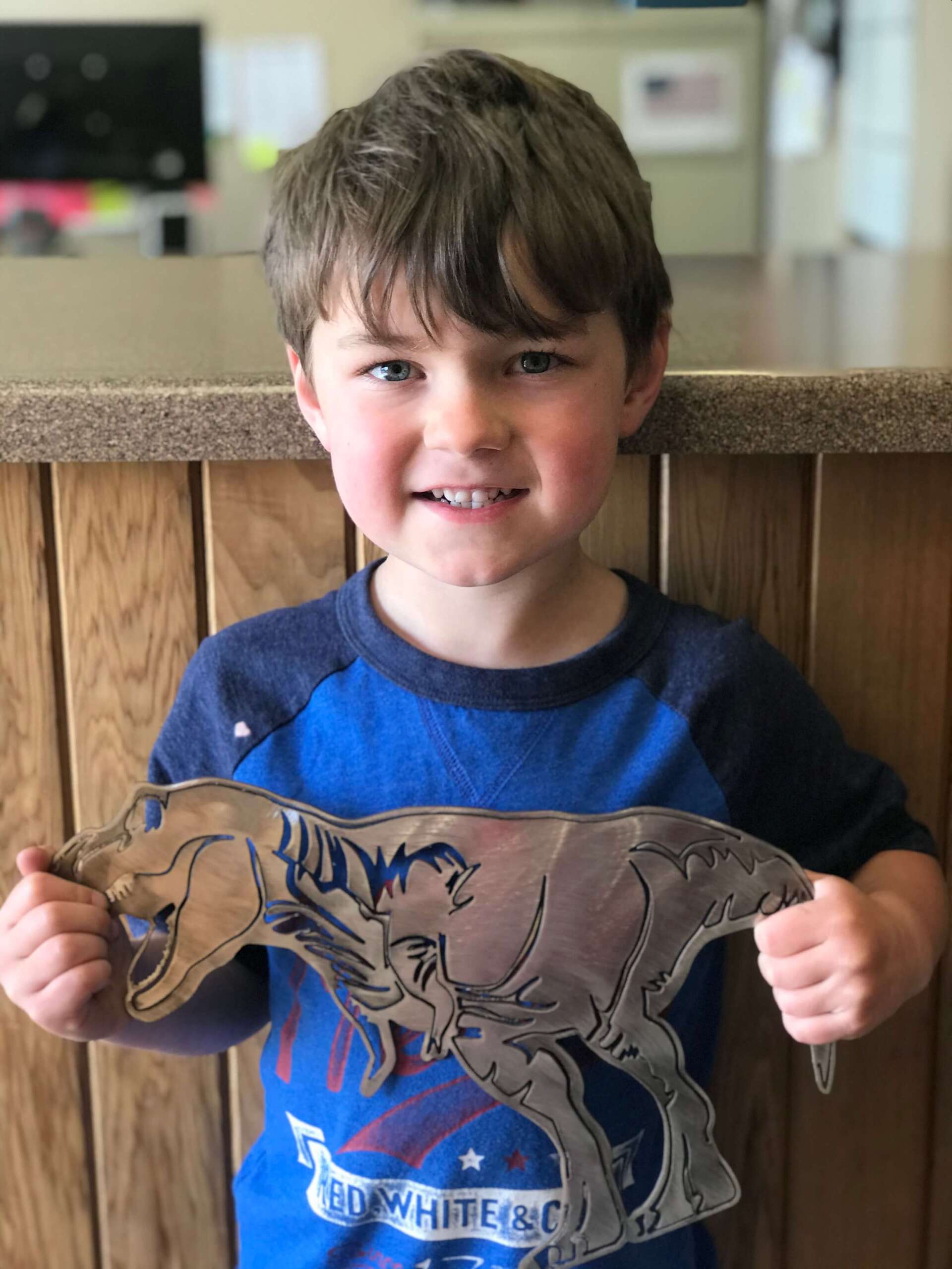 boy holding a t-rex metal art