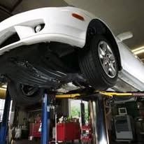 A white car is sitting on top of a lift in a garage.