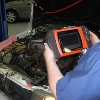 A man is using a diagnostic tool to check the engine of a car.