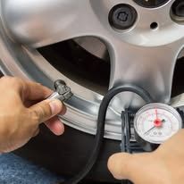 A person is checking the pressure of a tire with a gauge.