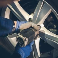 A person is changing a tire on a car with a wrench.