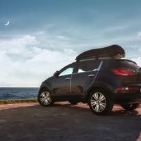 A car with a roof rack on top of it is parked next to the ocean.