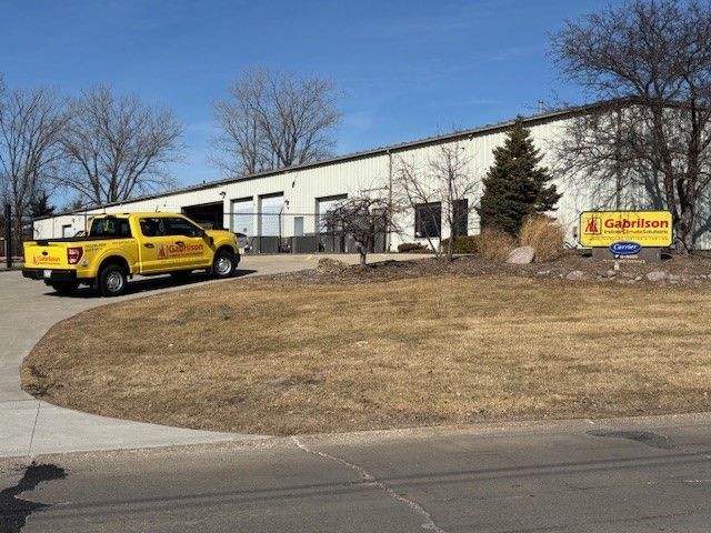 A yellow truck parked in front of a white commercial warehouse building with a sign that reads Gahrison.