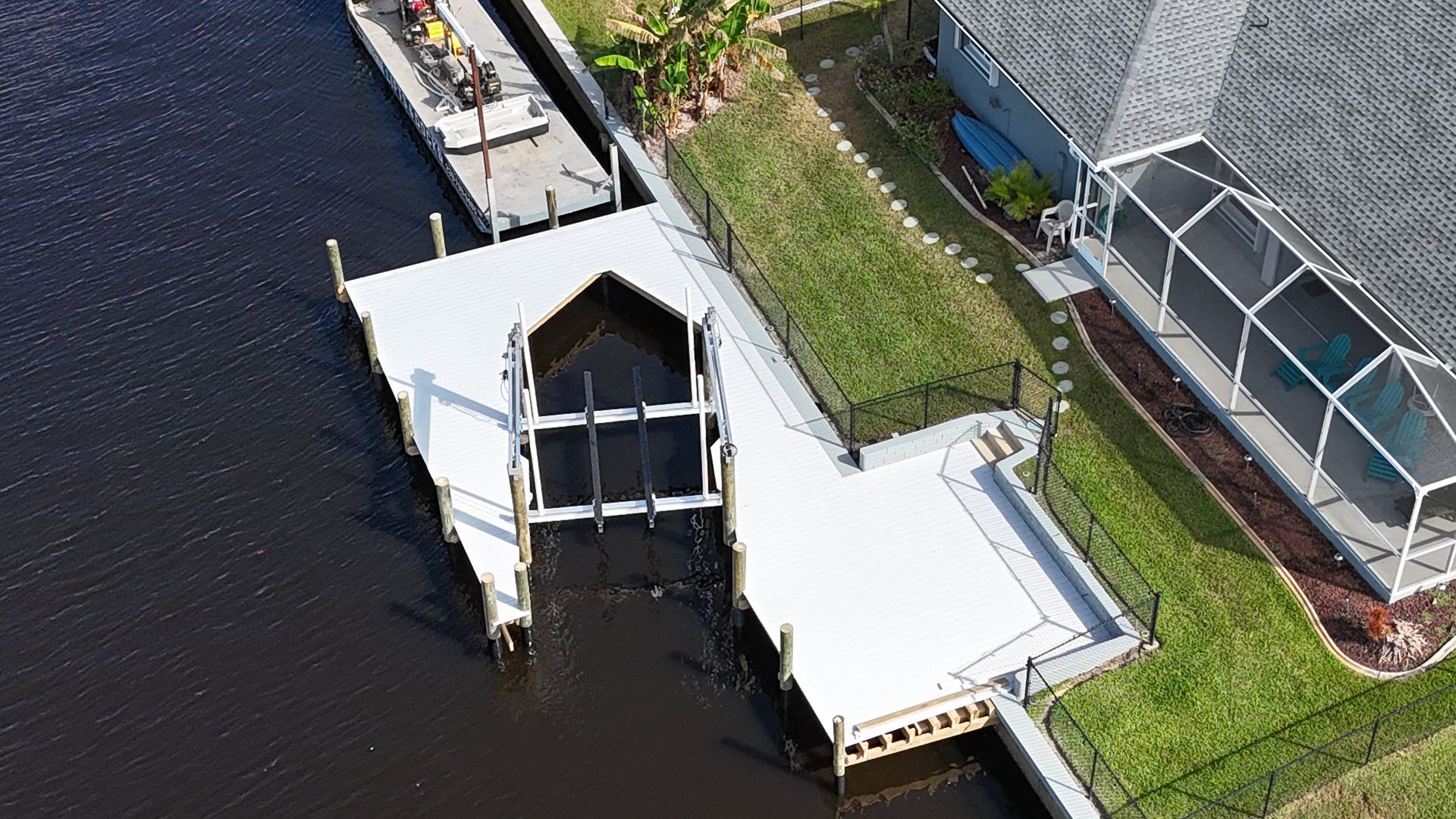 An aerial view of a dock in the water next to a house.