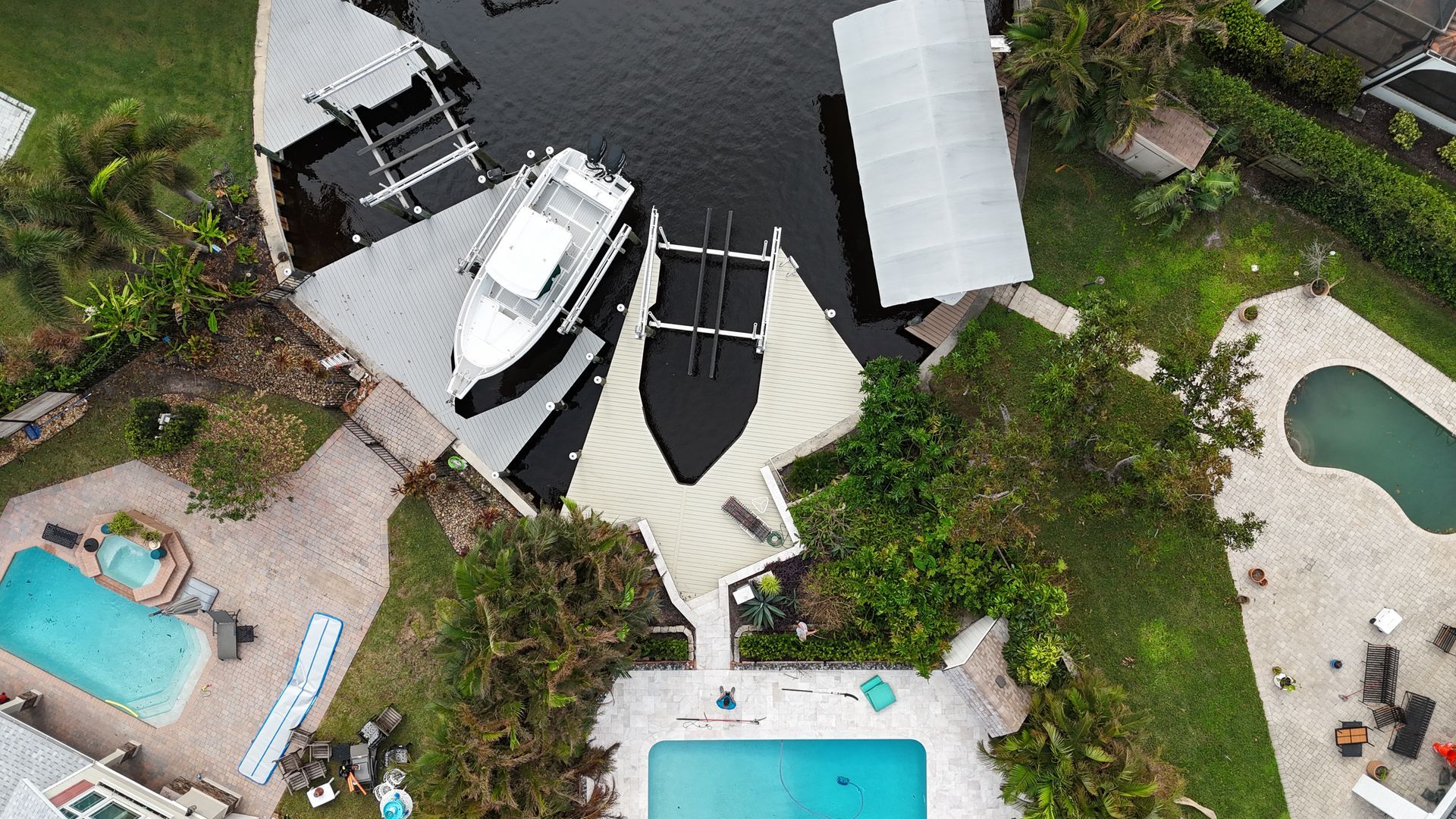 An aerial view of a house with a boat in the water and a pool.
