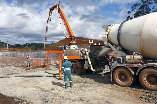 Construction workers beside cement mixer truck and orange crane at a building site