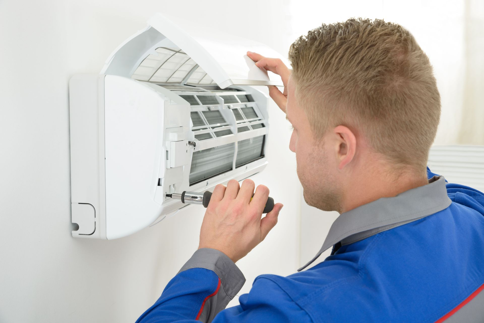 Technician cleaning an air conditioner unit mounted on a wall