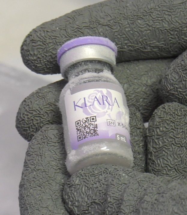 Gloved hand using a black handheld device on a person's neck
