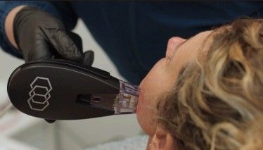 Gloved hand using a black handheld device on a person's neck