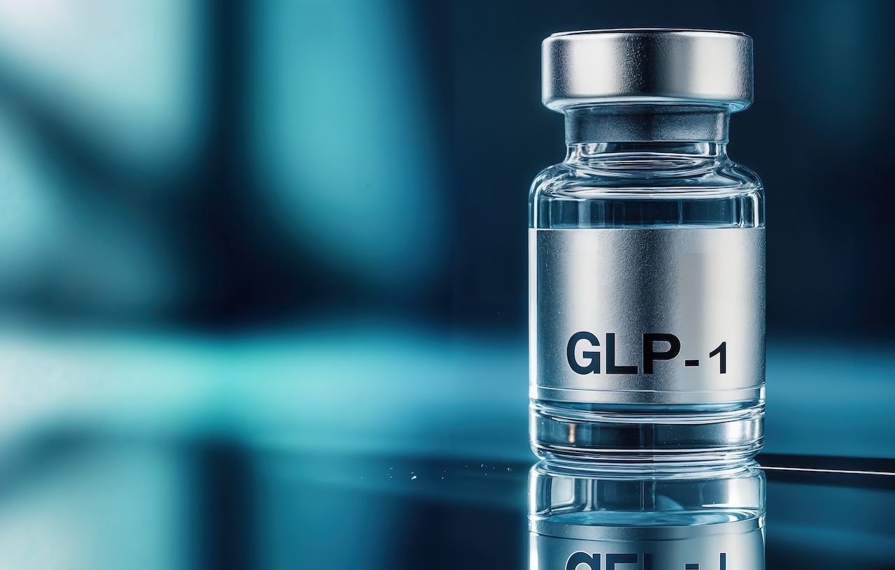 GLP-1 vial on a reflective surface with a blue blurred background