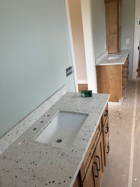 Bathroom with light-colored speckled countertops, cabinets, and a rectangular sink basin. Walls are light blue.