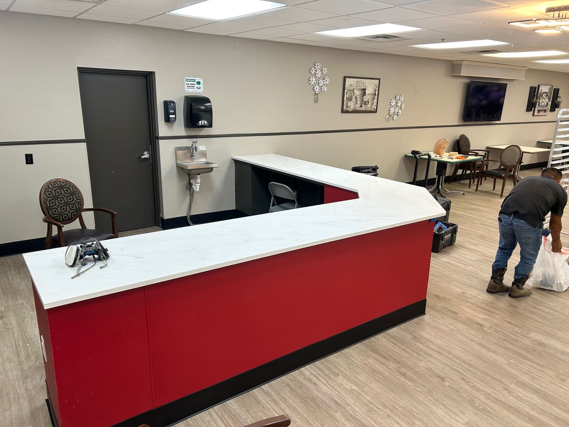 Red reception desk in a medical office; worker in jeans, carrying a bag.
