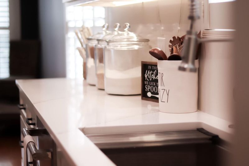 Kitchen countertop with jars, utensils, and sink.