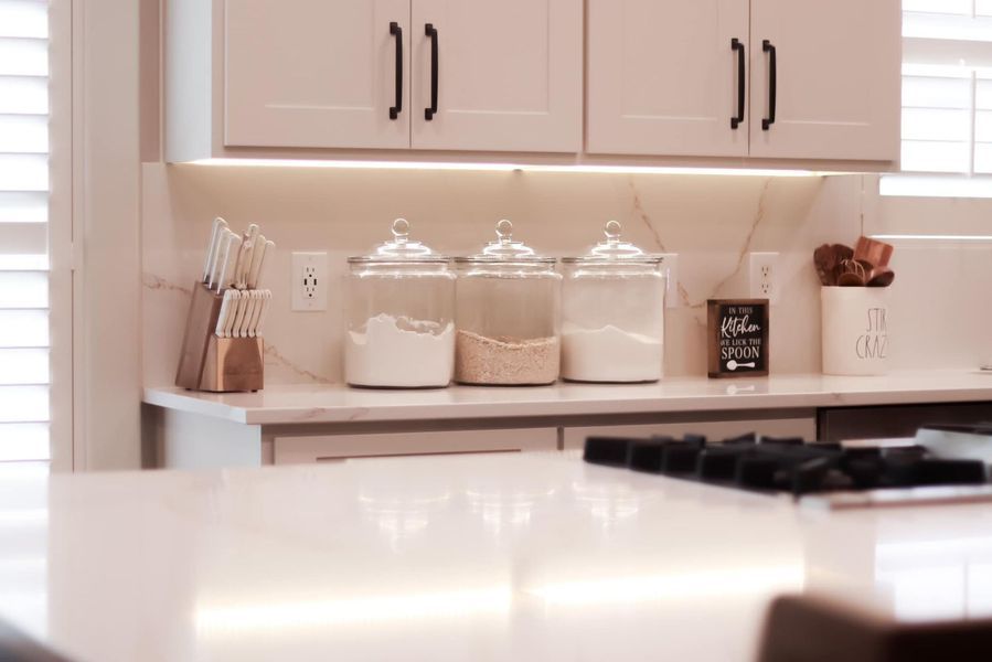 Kitchen counter with three glass jars, knives, and cabinets.