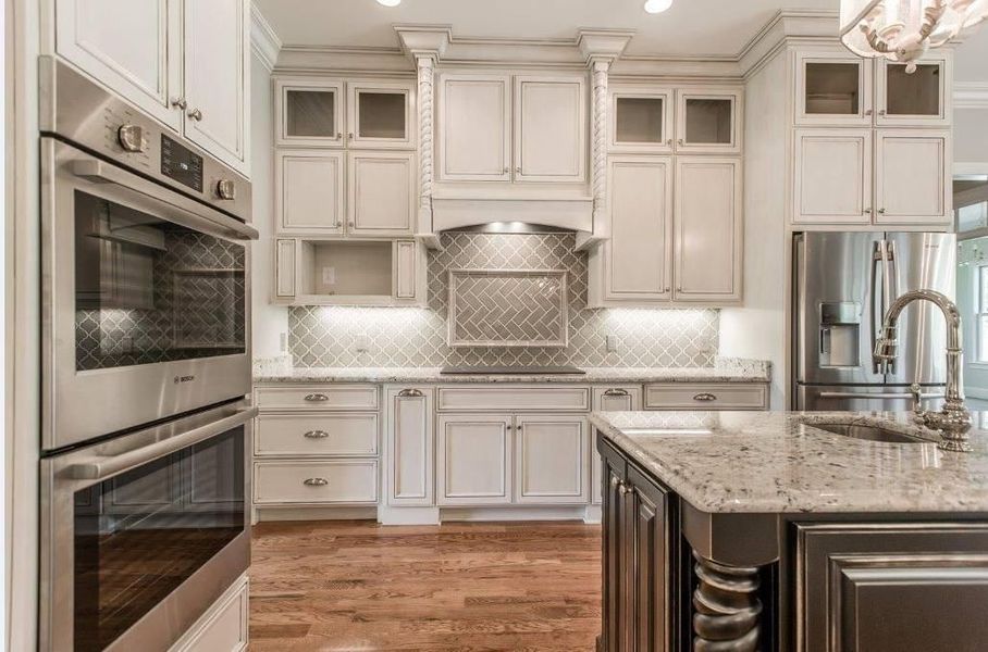 Elegant kitchen with white cabinets, stainless steel appliances, granite countertops, and a kitchen island.