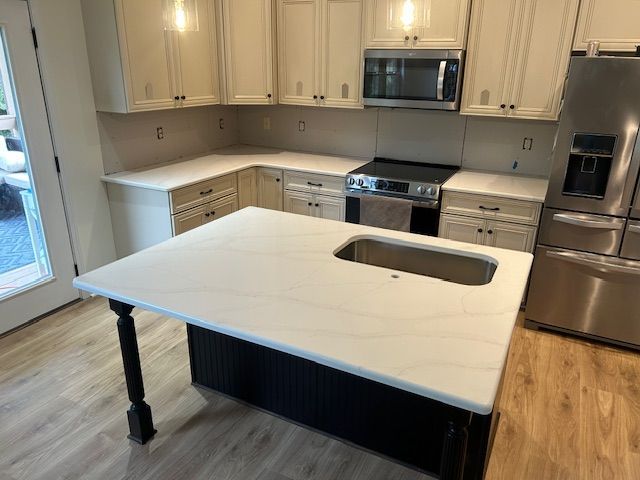 Kitchen with white countertops, island, cabinets, and stainless steel appliances.