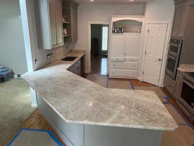 Kitchen with light countertops, cabinets, and appliances. A U-shaped island with a sink is present.