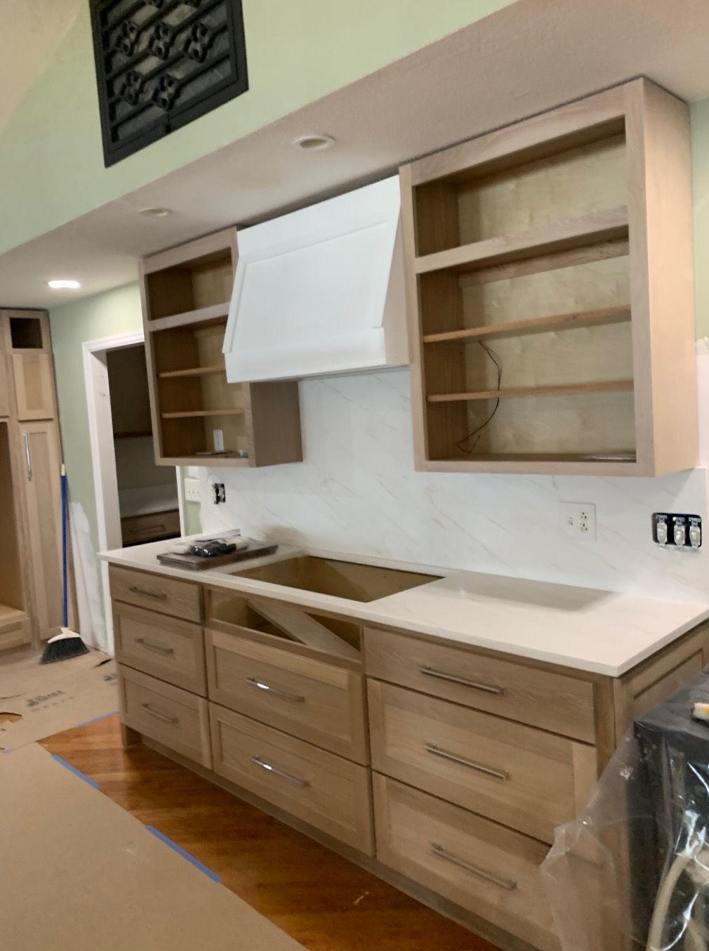 Kitchen under renovation with light wood cabinets, white countertops, and white backsplash.