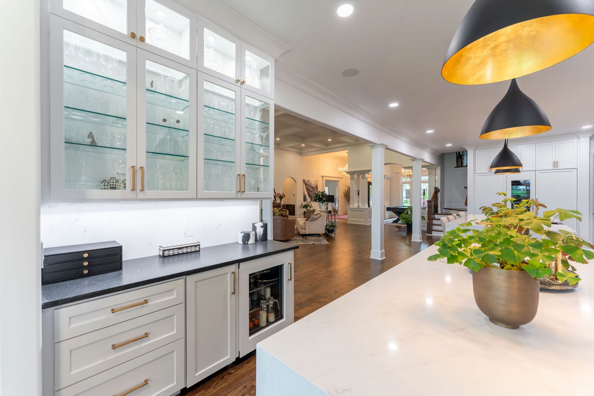 Kitchen with white cabinets, a black countertop, and a built-in wine cooler, with a view into a living area.