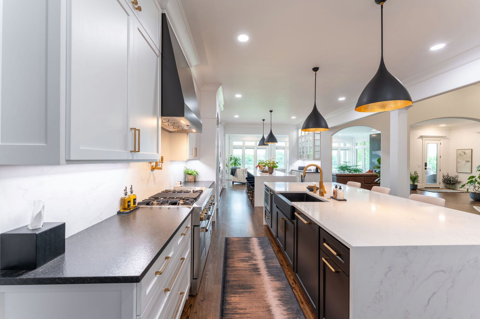 Modern kitchen with white cabinets, dark countertops, and large island with pendant lights.