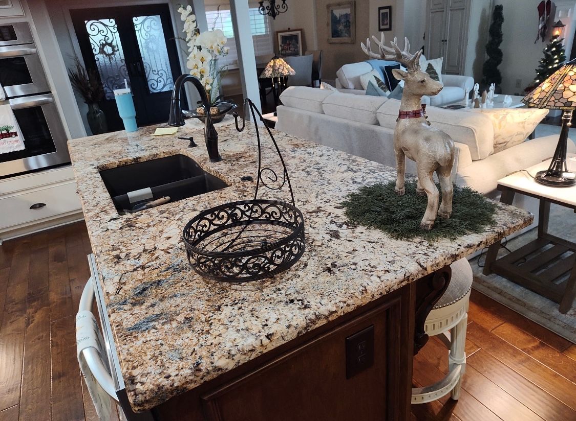 Kitchen island with granite countertop, sink, decorative deer, and a black basket.